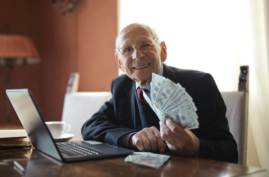 An elderly man holding cashnotes
